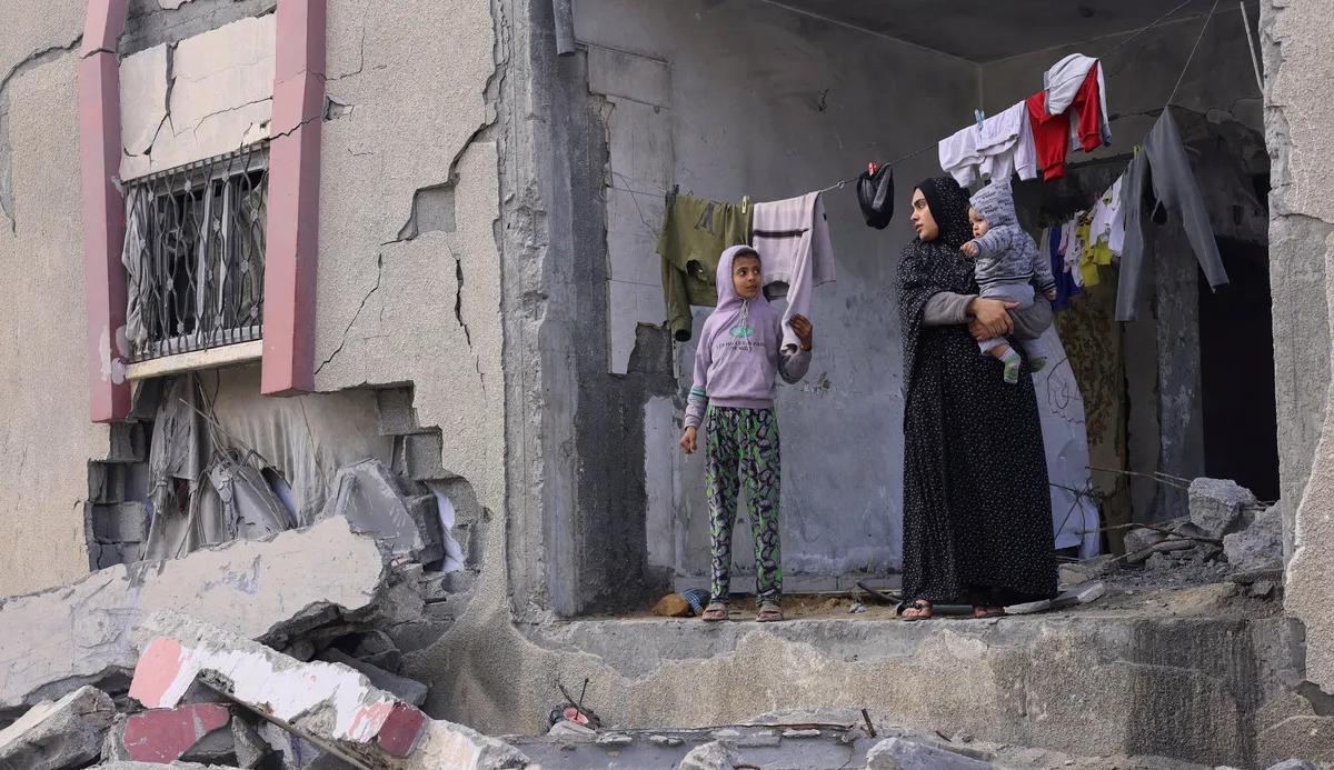 أم فلسطينية مع ولديها في منزلهم الذي دمره القصف الإسرائيلي  في غزة (نقلاً عن "هآرتس")
