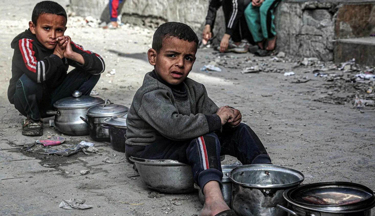 أطفال فلسطينيون ينتظرون الحصول على وجبة طعام في رفح في الأول من أمس (نقلاً عن "هآرتس")