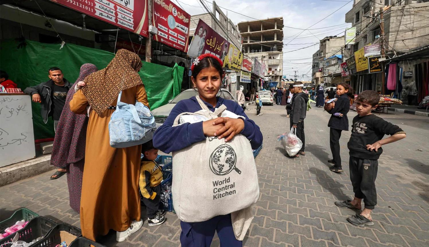 طفلة فلسطينية تحمل مساعدة غذائية من منظمة الاغاثة التي قتل 7  من موظفيها في قصف إسرائيلي في دير البلح (نقلاً عن "هآرتس")