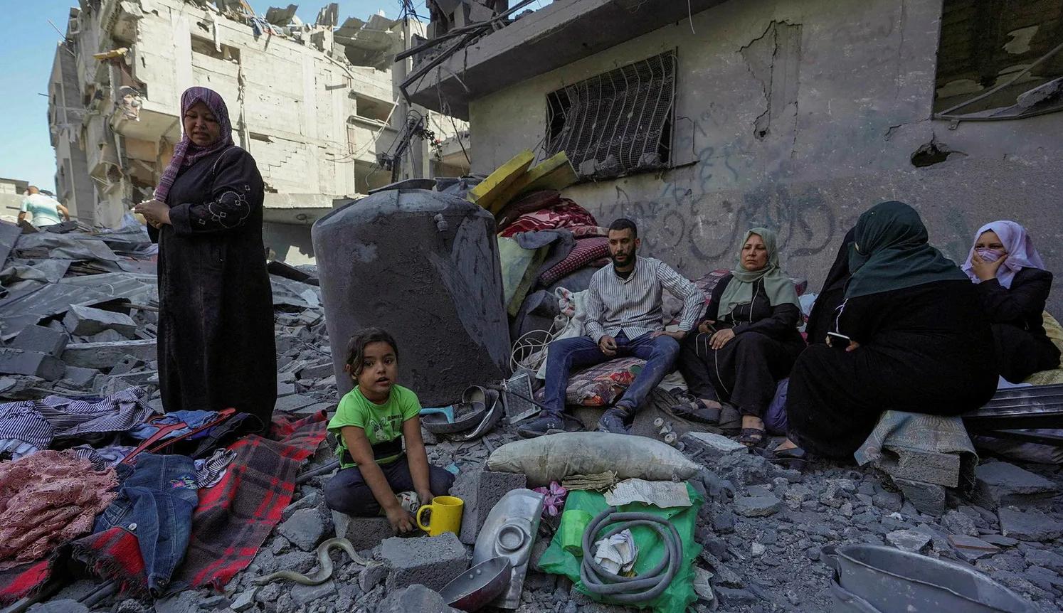 عائلة فلسطينية تجلس على أنقاض منزلها في غزة الذي دمره  القصف الإسرائيلي (نقلاً عن "هآرتس")