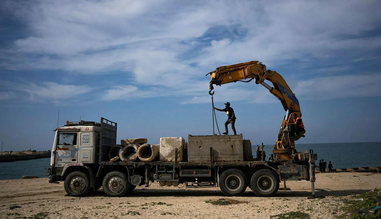 عمال فلسطينيون يساعدون في بناء الرصيف البحري في غزة  في الأمس (عن "هآرتس")