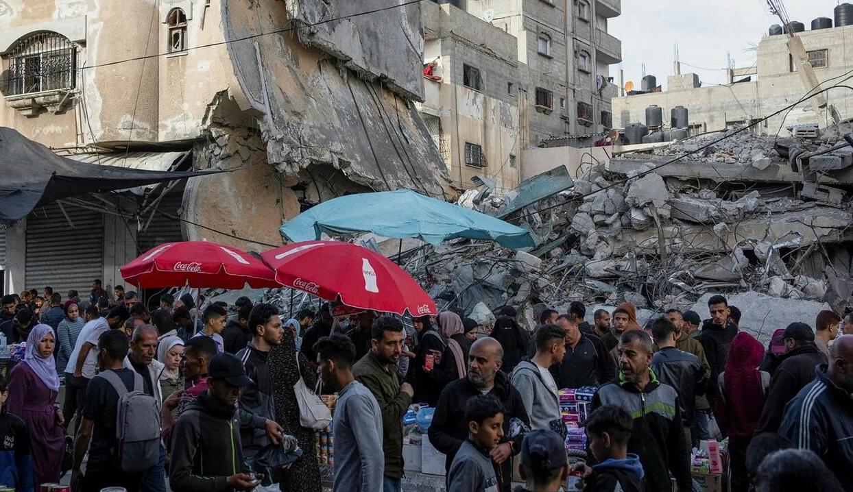 فلسطينيون في سوق محلي وسط الدمار الذي خلفه القصف الإسرائيلي  في مدينة رفح (عن "هآرتس")