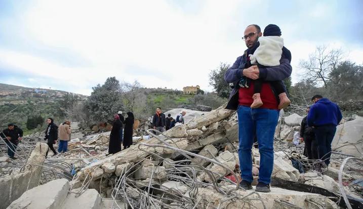 مواطنون لبنانيون يعاينون مبنى دمره القصف الإسرائيلي  في جنوب لبنان (عن "هآرتس")