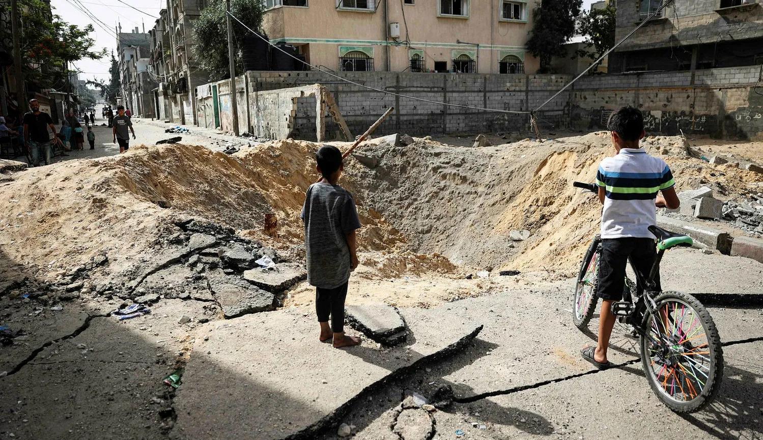طفلان فلسطينيان أمام حفرة خلفها القصف الإسرائيلي في رفح في الأول من أمس (نقلاً عن "هآرتس")